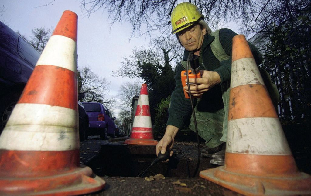 Mann prüft Gaskonzentration einer Gasleitung im Straßenbereich 