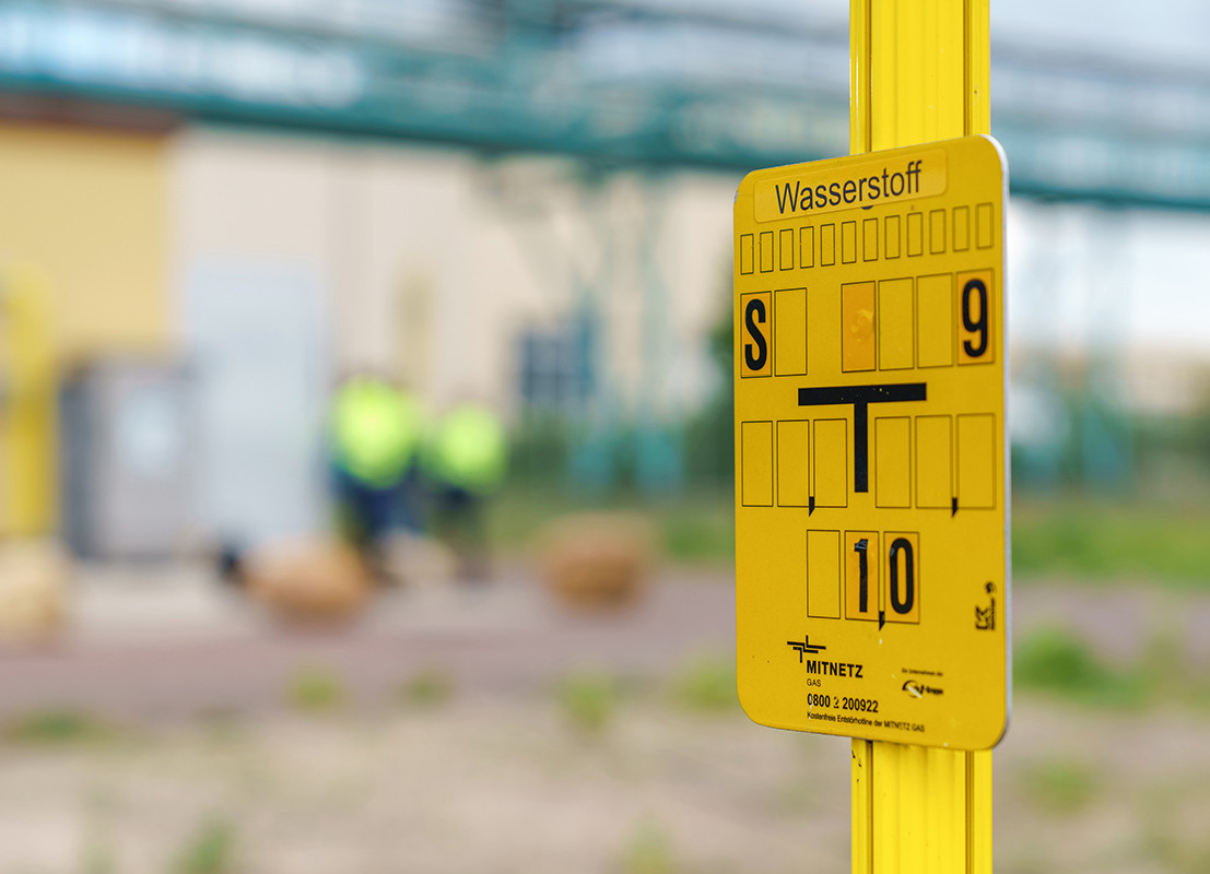 Ein gelbes Schild, das Auskunft über die Lage von Gas- und Wasserstoffleitungen im Boden gibt